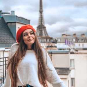 Mulher com blusa de frio branca e boina vermelha em Paris